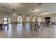 Large meeting room features neutral walls, tiled flooring, elegant chandeliers, arched windows, and tables for social gatherings at 6600 Sunset Way # 118, St Pete Beach, FL 33706