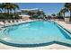 Large community swimming pool surrounded by lounge chairs and lush landscaping at 6600 Sunset Way # 118, St Pete Beach, FL 33706