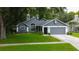Charming gray home features manicured lawn, two-car garage, and mature trees at 7320 Hideaway Trl, New Port Richey, FL 34655