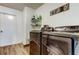 Well-lit laundry room featuring modern washer and dryer set, storage shelf, and wood-look vinyl floors at 7320 Hideaway Trl, New Port Richey, FL 34655