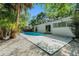 A private pool area features a fence, lush backyard trees, light gray concrete pool deck and white rock at 801 Lamont Pl, Temple Terrace, FL 33617
