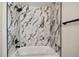 Modern bathroom featuring a white tub, black fixtures, and stylish marble-patterned tiling in the shower at 8108 Fir Dr, Tampa, FL 33619