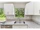 Close-up of the kitchen sink with granite countertops and white cabinets with a backyard view at 9936 62Nd N St, Pinellas Park, FL 33782