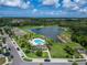 Beautiful community view featuring a pool, lake, lush greenery and well-maintained homes under a bright, cloudy sky at 10119 Rose Petal Pl, Riverview, FL 33578