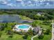 Aerial shot showcasing a luxurious pool area with lounge chairs, palm trees, and scenic lake views at 10119 Rose Petal Pl, Riverview, FL 33578