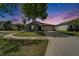 Charming single-story home with well-manicured lawn and a two-car garage at dusk at 10119 Rose Petal Pl, Riverview, FL 33578