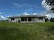 Rear exterior of home featuring an enclosed lanai, a large backyard, and mature landscaping at 1106 Trellis Ave, Spring Hill, FL 34606