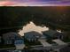 Aerial view of a residential community with a pond surrounded by green space at sunset at 11597 Weaver Hollow Rd, New Port Richey, FL 34654