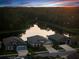 Aerial view of a residential community with a pond surrounded by green space at sunset at 11597 Weaver Hollow Rd, New Port Richey, FL 34654