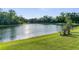Picturesque view of a lush backyard leading to a serene lake with two wooden chairs on the grass at 11597 Weaver Hollow Rd, New Port Richey, FL 34654