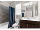 Bathroom featuring dark wood vanity with white countertops, framed mirror, and tiled bathtub with blue shower curtain at 11597 Weaver Hollow Rd, New Port Richey, FL 34654