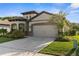 View of a single-Gathering home featuring a two-car garage, beautiful landscaping and modern architecture at 11597 Weaver Hollow Rd, New Port Richey, FL 34654