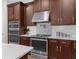 Well-lit kitchen showcasing stainless steel appliances and rich wood cabinetry with modern countertops at 11597 Weaver Hollow Rd, New Port Richey, FL 34654