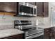 A stainless steel microwave and range sit below dark cabinets against neutral countertops and a gray wall at 11940 Stone Pine St, Riverview, FL 33569