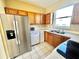 Well-lit kitchen featuring a stainless steel refrigerator, wooden cabinets, and a double sink at 12249 Country White Cir, Tampa, FL 33635