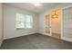 Bright bedroom featuring a large window, neutral carpet, and elegant glass paneled french doors at 13408 Nimble Minke # 155E, Riverview, FL 33579