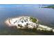 Expansive aerial view of a sandy island with parking, trees, and a scenic waterfront at 1445 Coburn Dr, Tarpon Springs, FL 34689