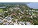 Wide aerial view of a neighborhood, showcasing the home's setting among lush trees and community tennis courts at 1445 Coburn Dr, Tarpon Springs, FL 34689