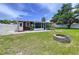 Cozy backyard features a fire pit, green lawn, a white fence, and a small building at 1445 Coburn Dr, Tarpon Springs, FL 34689