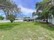 Expansive backyard with green lawn, privacy fence, mature trees, and the exterior of home at 1445 Coburn Dr, Tarpon Springs, FL 34689