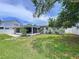 Well-maintained backyard featuring green lawn, mature trees, landscaping, and patio area at 1445 Coburn Dr, Tarpon Springs, FL 34689