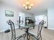 Dining room with glass table, decorative chandelier, and view into living area with fish tank at 1445 Coburn Dr, Tarpon Springs, FL 34689