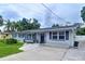 Charming single-story home featuring a well-manicured lawn, dark shutters and a beautiful palm tree at 1445 Coburn Dr, Tarpon Springs, FL 34689