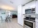 Modern kitchen features stainless steel appliances, white cabinets, and an adjacent dining area at 1445 Coburn Dr, Tarpon Springs, FL 34689