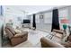 Bright living room featuring two leather sofas, ceiling fan, and large windows with ample natural light at 1445 Coburn Dr, Tarpon Springs, FL 34689