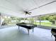 Enclosed patio features a pool table, fan, and clear views of the backyard greenery and white fence at 1445 Coburn Dr, Tarpon Springs, FL 34689