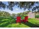 Picturesque backyard with a view of the lake, featuring comfortable red Adirondack chairs and a storage shed at 15316 Winding Creek Dr, Tampa, FL 33613