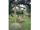 Backyard showcasing a charming wooden swing set, offering a peaceful spot to relax under the shade of mature trees at 15316 Winding Creek Dr, Tampa, FL 33613