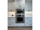 Modern kitchen boasts stainless steel wall ovens and sleek white cabinetry at 15316 Winding Creek Dr, Tampa, FL 33613