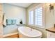 Modern bathroom with soaking tub, wooden-look tile floors, and a shuttered window at 1592 Cumberland E Ct, Palm Harbor, FL 34683