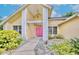Charming home exterior featuring lovely landscaping and a welcoming pink front door at 1592 Cumberland E Ct, Palm Harbor, FL 34683