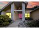Charming home exterior with a pink front door, lovely landscaping, and a welcoming entrance at 1592 Cumberland E Ct, Palm Harbor, FL 34683