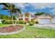Charming home featuring a bright pink door and lush landscaping with a palm tree and well-manicured lawn at 1592 Cumberland E Ct, Palm Harbor, FL 34683