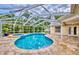 Inviting screened-in pool and spa area with a paver deck and tropical greenery at 1592 Cumberland E Ct, Palm Harbor, FL 34683