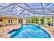 This screened-in pool and spa area features a tile deck and tropical landscaping at 1592 Cumberland E Ct, Palm Harbor, FL 34683