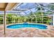 Screened-in pool area with a sparkling pool and lush tropical landscaping surrounding the enclosure at 1592 Cumberland E Ct, Palm Harbor, FL 34683