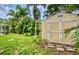 Exterior view of a backyard shed surrounded by lush greenery and tropical plants at 1592 Cumberland E Ct, Palm Harbor, FL 34683