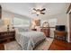 Comfortable bedroom with a ceiling fan, wood floors, a bed with decorative pillows, and vintage furniture at 2140 Bow Ln, Safety Harbor, FL 34695