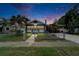 Twilight view of a charming single-story home with manicured lawn and gated front yard, set against a colorful sky at 2334 14Th N Ave, St Petersburg, FL 33713