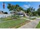 Cozy one-story home showcasing a lush front yard, a blossoming tree, and a secure gated entrance at 2334 14Th N Ave, St Petersburg, FL 33713