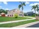 A charming two-story home with a well-manicured lawn and lush palm trees, showcasing its appealing curb appeal at 277 Wood Dove Avenue, Tarpon Springs, FL 34689