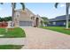 Beautiful home featuring a brick driveway, well-kept lawn, and mature palm trees, exhibiting its outdoor charm at 277 Wood Dove Avenue, Tarpon Springs, FL 34689