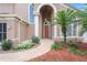 Close up of the front door with an arched entryway, lush landscaping, and a brick walkway at 277 Wood Dove Avenue, Tarpon Springs, FL 34689
