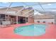 View of a kidney-shaped pool with screening, red painted concrete, and steps for easy entry at 277 Wood Dove Avenue, Tarpon Springs, FL 34689