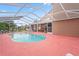 View of a kidney-shaped pool with screening, red painted concrete, and a glimpse of the interior at 277 Wood Dove Avenue, Tarpon Springs, FL 34689