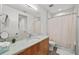 Bright bathroom with a wood vanity, a granite countertop, large mirror, tiled walls, and a shower with curtain at 2803 W Aquilla St, Tampa, FL 33629